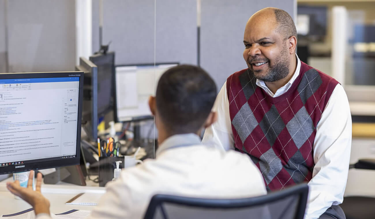 Two men working and in discussions at a desk.