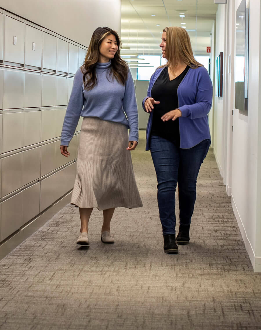 Two women walking down the hall talking.